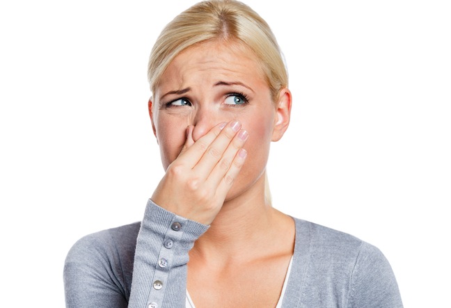 Woman holding nose smelling stinky odor